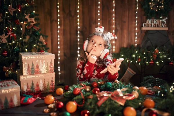 Fille en utilisant le téléphone près de l'arbre de Noël à l'intérieur décoratif. Noël et Nouvel An photo. — Photo