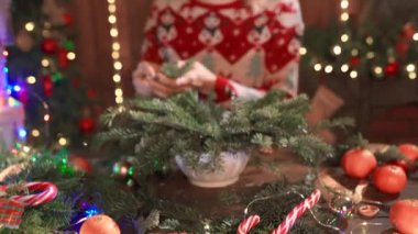 Noel tasarımı süveter giymiş bir kadın Noel için el yapımı Noel çelengi yapıyor. Noel dekorasyonu ve kompozisyonu