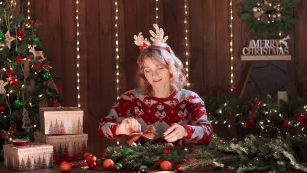 크리스마스 때 디자인 한 스웨터를 입은 여자가 손으로 만든 크리스마스 선물을 식탁에 올려 놓고 연휴를 보내고 있습니다. 크리스마스 장식 과작 물 — 비디오