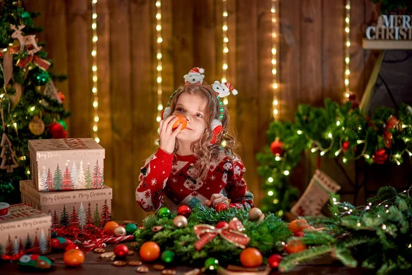 Little girl decorating coniferous wreath near Christmas tree in the decorative interior. Christmas and New Year photo — Stock Photo, Image