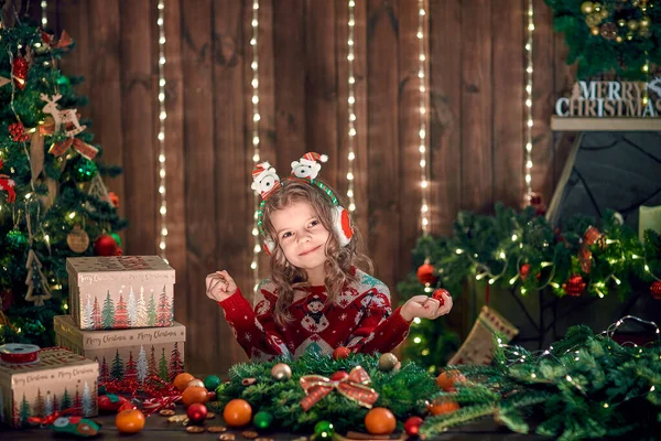 Petite fille décorant une couronne de conifères près du sapin de Noël à l'intérieur décoratif. Noël et Nouvel An photo — Photo