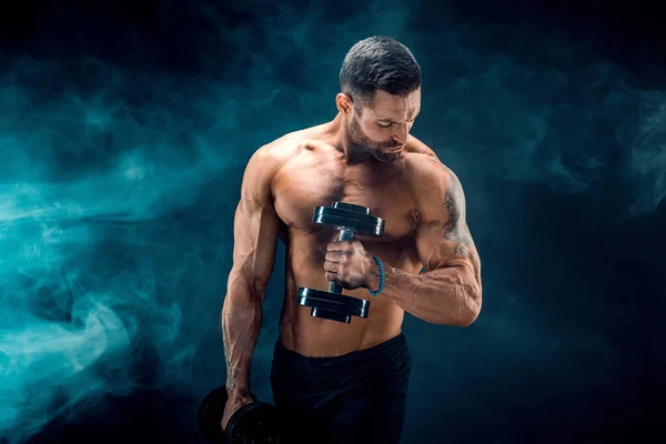 Jonge gescheurde man bodybuilder met perfecte buikspieren, schouders, biceps, triceps en borst poseren met een halter — Stockfoto