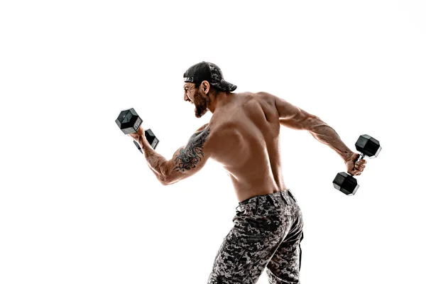 Muscular atleta culturista hombre en pantalones de camuflaje con un torso desnudo perforando con mancuernas como boxeador sobre un fondo blanco — Foto de Stock