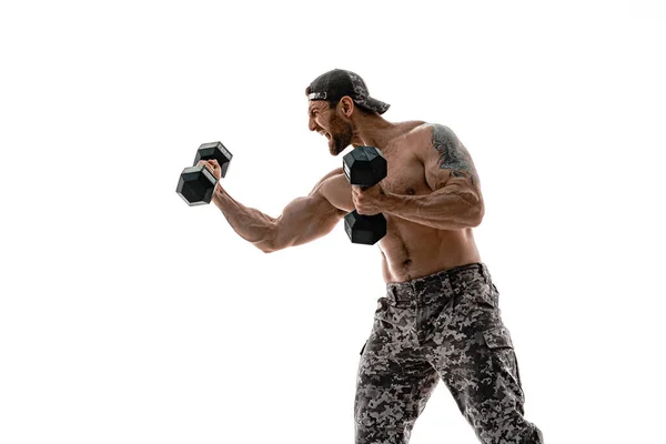 Gespierde atleet bodybuilder man in camouflage broek met een naakte romp ponsen met halters als bokser op een witte achtergrond — Stockfoto