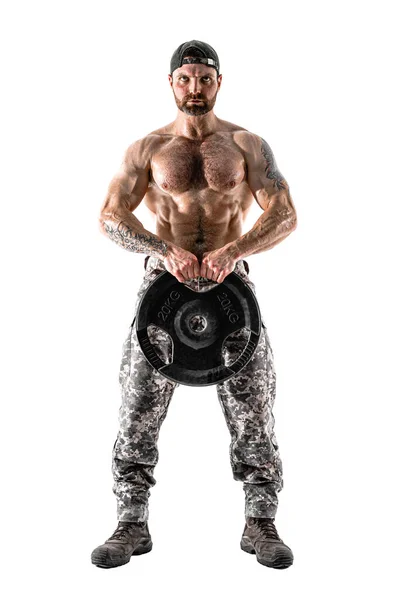 Atleta musculoso musculoso homem em calças de camuflagem com um treino de tronco nu com haltere em um fundo branco. — Fotografia de Stock