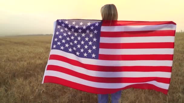 Žena běží a skákání bezstarostné s otevřenou náručí přes pšeničné pole Holding USA vlajka — Stock video