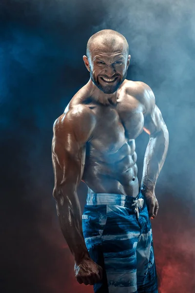 Handsome strong bodybuilder posing in studio on black background — Stock Photo, Image