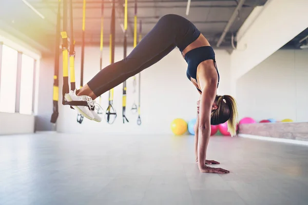 Mooie jonge vrouw training met suspension trainer sling of vering riemen in de sportschool. Oefenconcept voor bovenlichaam op TRX — Stockfoto