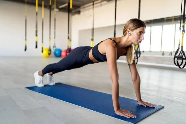 Volledige lengte van jonge mooie vrouw in sportkleding doen plank en werken haar kernspieren in de sportschool — Stockfoto