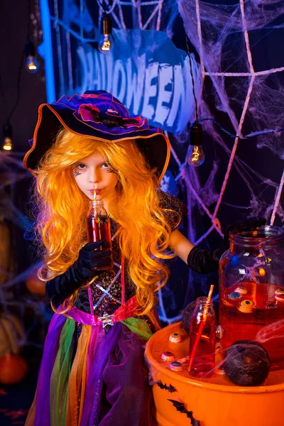 Malá krásná dívka v kostýmu čarodějnice slaví Happy Halloween party v interiéru s dýněmi — Stock fotografie