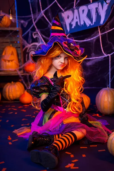 Μικρό όμορφο κορίτσι σε ένα κοστούμι μάγισσα γιορτάζει Happy Halloween κόμμα στο εσωτερικό με κολοκύθες — Φωτογραφία Αρχείου