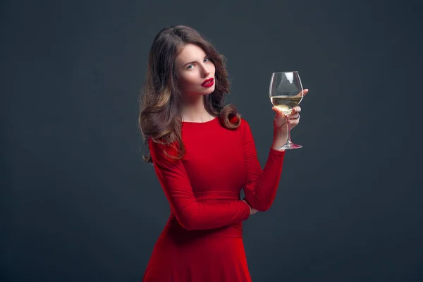 Nő fényes smink, frizura visel piros ruhát pózol üveg szőlő felett sötét háttér, izolálni — Stock Fotó