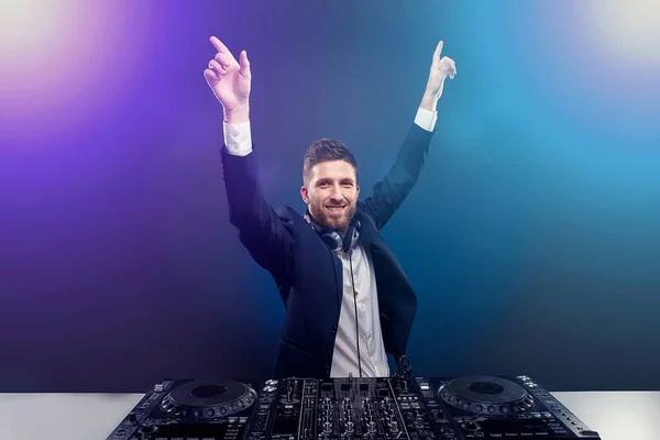 Man DJ en costume sombre joue de la musique sur un mixeur Djs. Prise de vue. Fond bleu foncé — Photo
