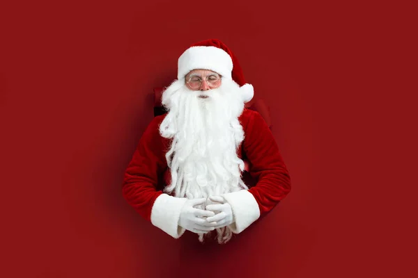 Mikołaj medytujący przez dziurę w papierze. Zniżka. Sprzedaż świąteczna. Świąteczne dekoracje. Miejsce na tekst. Projekt plakatu wakacyjnego, baner — Zdjęcie stockowe