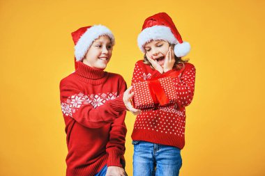 Çocuk şaşırmış kıza Noel hediyesi veriyor.