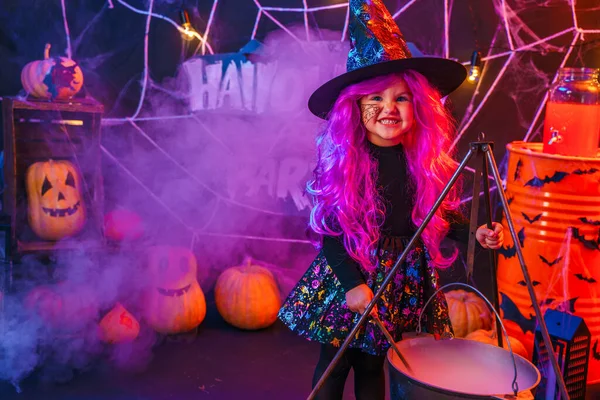 Kleines hübsches Mädchen im Hexenkostüm feiert Happy Halloween Party im Innenraum mit Kürbissen — Stockfoto