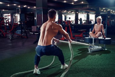 Fitness adamı spor salonunda halatlarla çalışıyor.