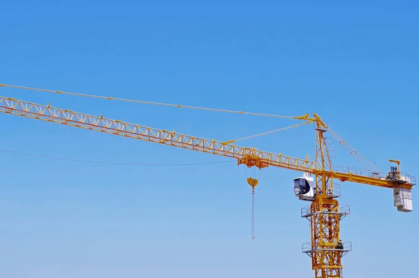 yellow construction crane tower on background of blue sky