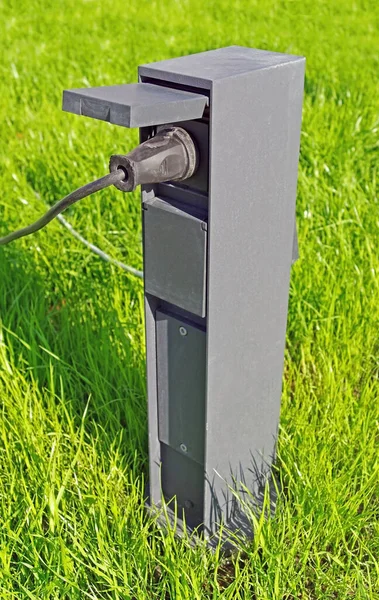 Outdoor electric plug on a lawn with green grass