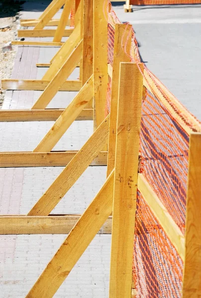 orange grid of barrier tape on wooden fence for construction site