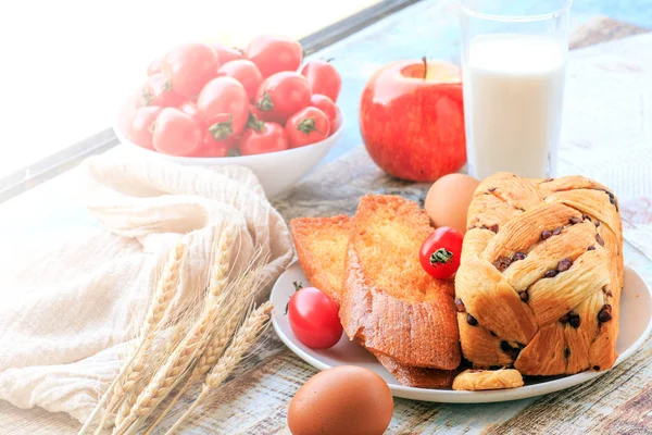 Bread, milk, eggs and fruit are on the table