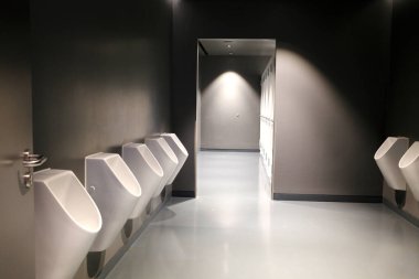 Erkekler tuvaletinde beyaz pisuarlar. Erkekler tuvaletinde arka arkaya seramik pisuarlar. İdrar kesesi sağlığı ve idrar tutamama sorunu. Regensburg 'de. Almanya.