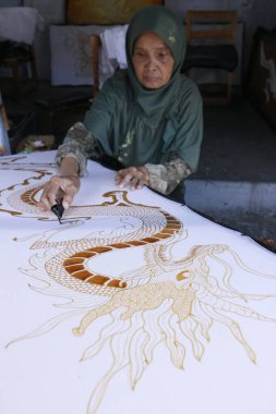 Batik Prodüksiyon. Kadın ejderha tasarımı için sıcak balmumu kullanıyor. Yogyakarta. Endonezya.