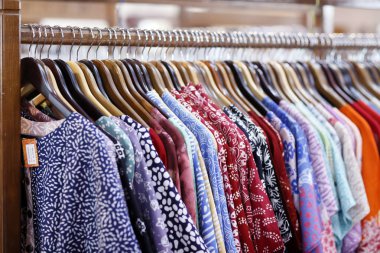 Batik Prodüksiyon. Batik geleneksel Endonezya giysisidir. Satış odasındaki askılarda tişörtler. Yogyakarta. Endonezya.