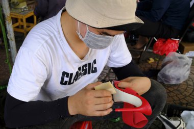 Caddedeki ayakkabı tamircisi. El işçiliği. Ho Chi Minh Şehri. Vietnam.