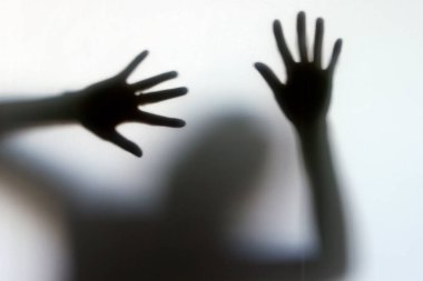 Camın arkasında bir kadının silueti. Jest yapan bir kadın. Kadınlara yönelik şiddeti ve cinsel istismarı durdurun. Hüzün ve kriz konsepti.