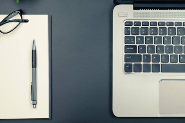 Dizüstü bilgisayar ve boş defter kalem ve gözlük vintage sesi ile tablo üstten görünüm