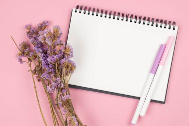 Pembe arka plan üzerinde dizüstü bilgisayar ve menekşe çiçek üst görünümü
