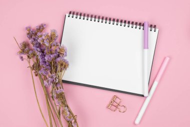 Pembe arka plan üzerinde dizüstü bilgisayar ve menekşe çiçek üst görünümü
