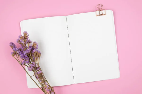 Notizbuch und violette Blume auf rosa Hintergrund — Stockfoto