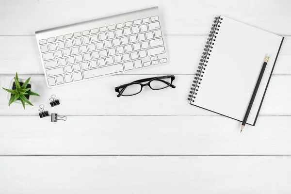 Top view of minimal office desk with an open blank notebook and