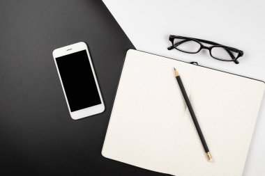 Kalem ve akıllı telefon ile boş bir ızgara dizüstü bilgisayar üst görünümü