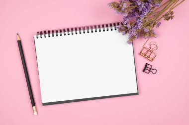 Pembe arka plan üzerinde dizüstü bilgisayar ve mor çiçek üst görünümü