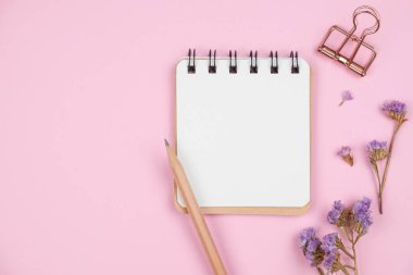 Pembe arka plan üzerinde mor çiçekli boş dizüstü bilgisayarın üst görünümü