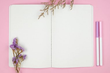 Notebook kırtasiye ve çiçek pembe bir arka plan üzerinde Üstten Görünüm