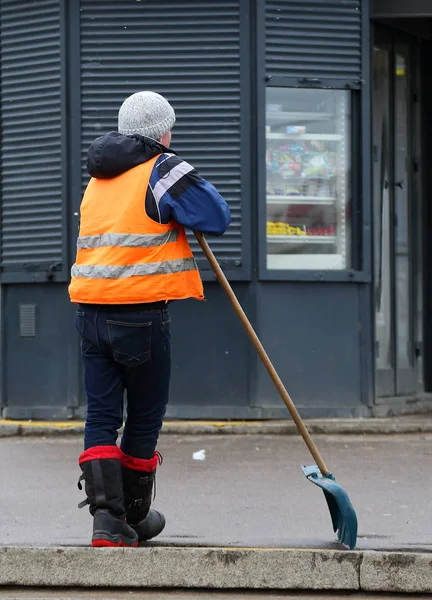 Turuncu bir yelek kapıcı bir kürek yaslanmış