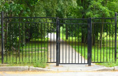 Kilitli bir kapı ile metal bir çit arkasında bahçede Park yolu