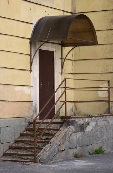 Entrance to the building with a stone porch and a metal door