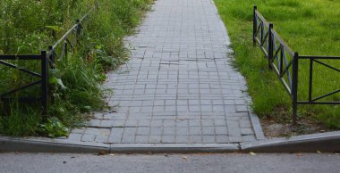 Çitle çevrili Park yolu kaldırım levhaları ile kaplı