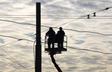 Yükselen kablolar arka planda bulutlu bir gökyüzünde yüksek irtifada çalışan yükleyiciler