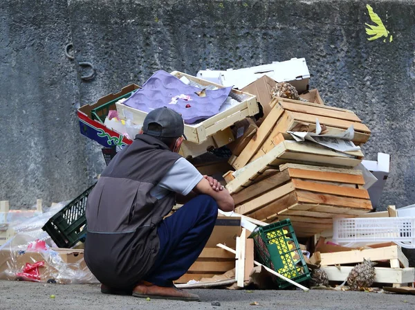 Bir Adam Çöp Yığınının Önünde Beton Bir Duvara Doğru Çömeliyor — Stok fotoğraf