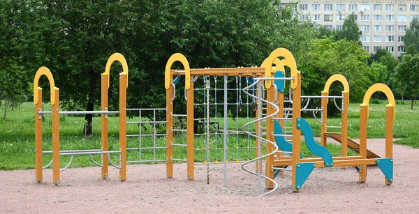 緑の中庭にある黄色の子供の遊び場 — ストック写真
