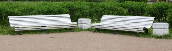 Zwei Weiße Hölzerne Parkbänke Mit Einem Mülleimer Dazwischen — Stockfoto