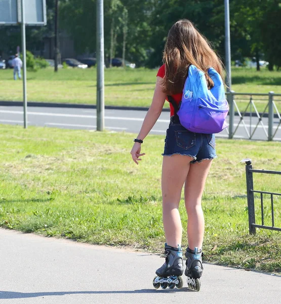 A girl in short shorts on roller skates rides on a Park track, Iskrovsky prospekt, Saint Petersburg, Russia June 2020