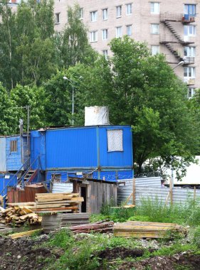 Bahçedeki bir inşaat alanında mavi kulübeler ve keresteler.