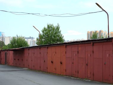 Avluda kırmızı metal garajlar var.